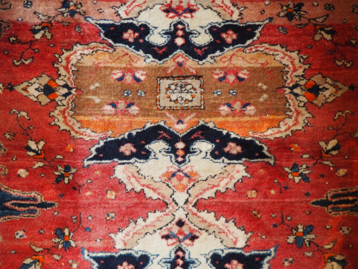 Tapis d'Orient ancien en laine fond rouge. Dim. 313 x 44 cm.