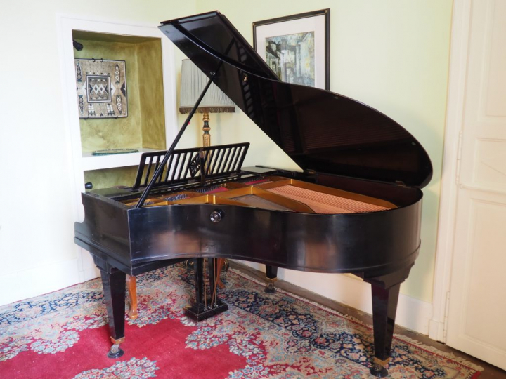 Piano quart de queue Berchstein en bois laqué noir cadre fer.