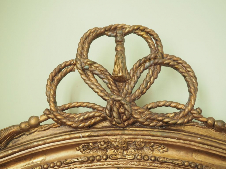 Miroir ovale de style Louis XVI, cadre en bois et stuc doré à décor de