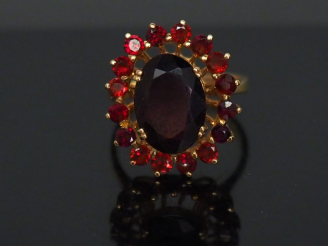 Vente aux enchères 	Bague marguerite en or jaune, sertie d’un grenat central entouré de s