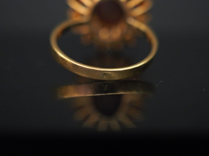 	Bague marguerite en or jaune, sertie d’un grenat central entouré de s