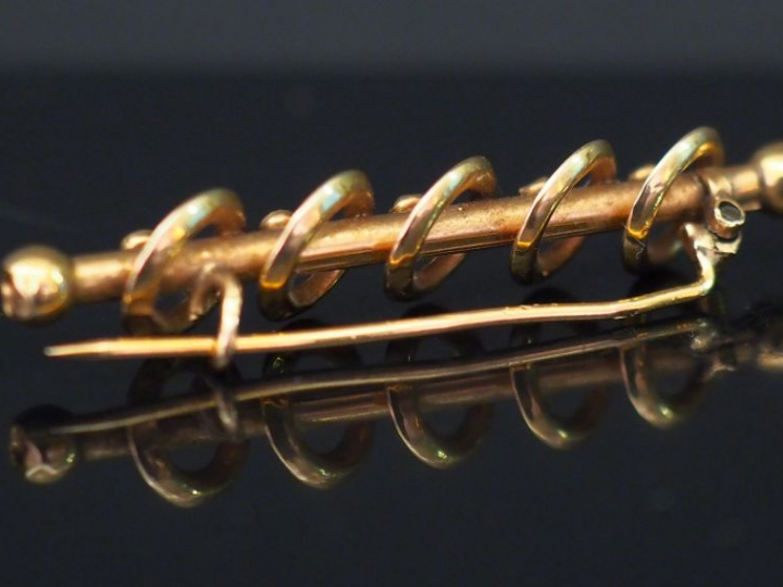 Broche barrette en or jaune, à décor de cercles entourant une tige cen