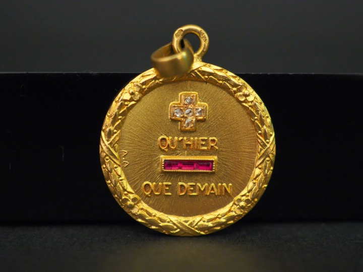 Médaille en or jaune, marquée « + qu’hier - que demain », sertie de ci