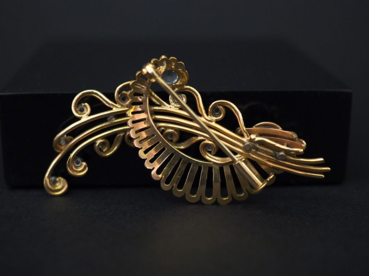 	Broche en or jaune, en forme de tiges fleurie enrubannée, sertie de s