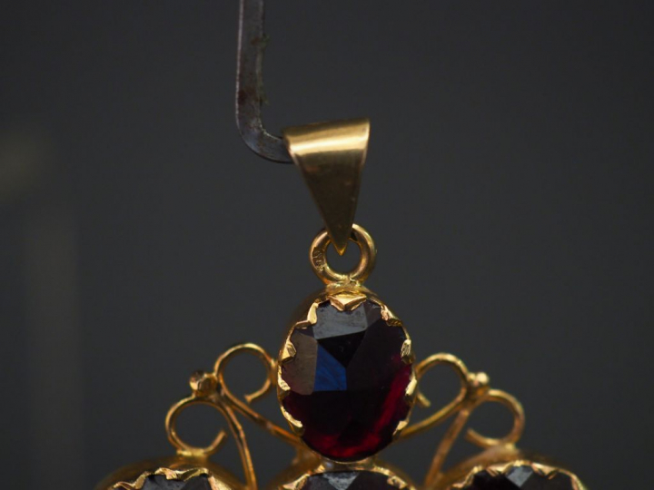 	Pendentif en forme de croix en or jaune, serti de six grenats, décor 