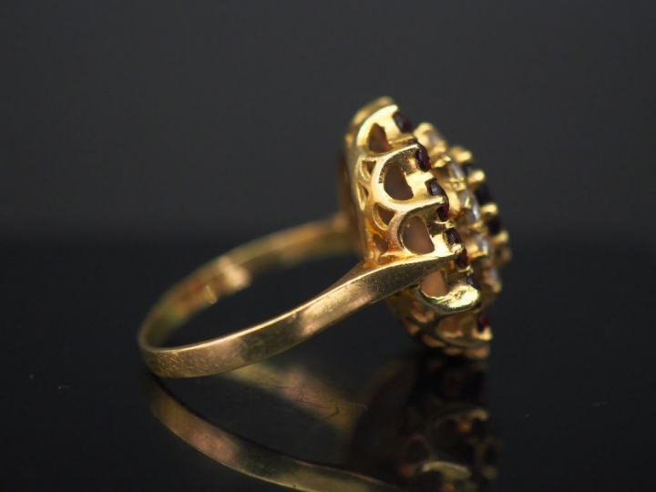 	Bague marguerite en or jaune, sertie en son centre d’un grenat entour