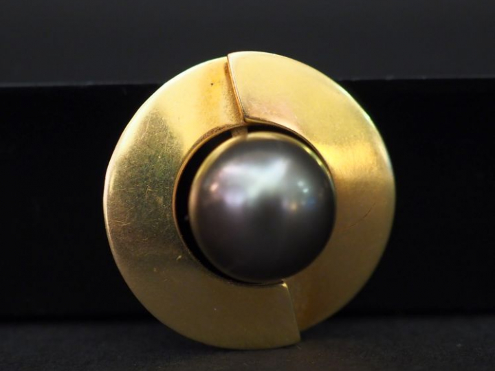 Pendentif rond en or jaune, sertie en son centre d’une perle grise. Di