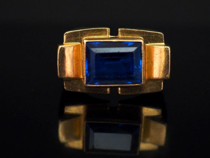 Bague tank en or jaune, sertie en son centre d’une pierre bleue. TDD. 