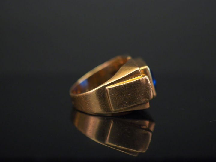 Bague tank en or jaune, sertie en son centre d’une pierre bleue. TDD. 