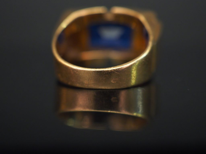 Bague tank en or jaune, sertie en son centre d’une pierre bleue. TDD. 