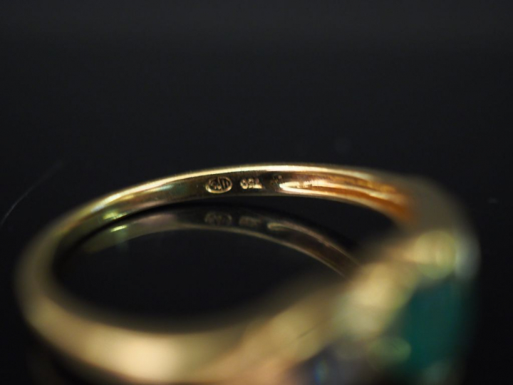 Bague en or jaune, sertie en son centre d’une émeraude épaulée de deux