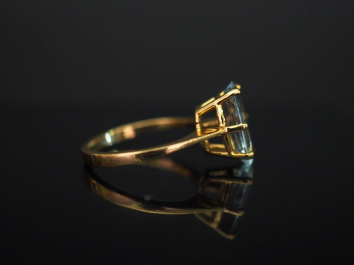 Bague en or jaune, sertie en son centre d’une pierre bleu ciel. TDD. 4