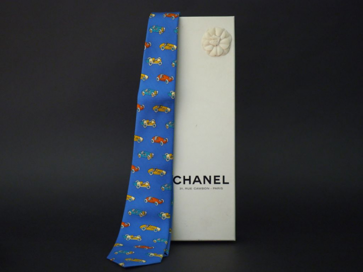 	CHANEL Cravate en soie bleue, à décor polychrome de voitures. Signée.