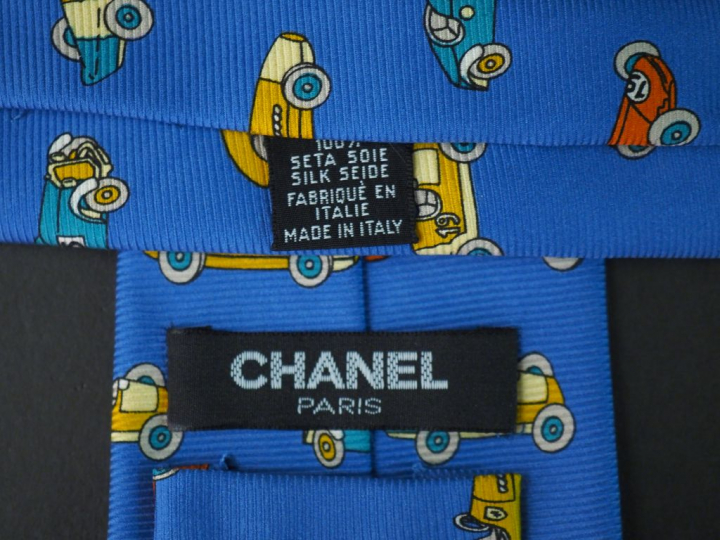 	CHANEL Cravate en soie bleue, à décor polychrome de voitures. Signée.