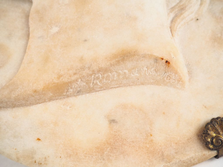 ROMAND. Plaque ovale en albâtre sculpté figurant un profil de jeune fe