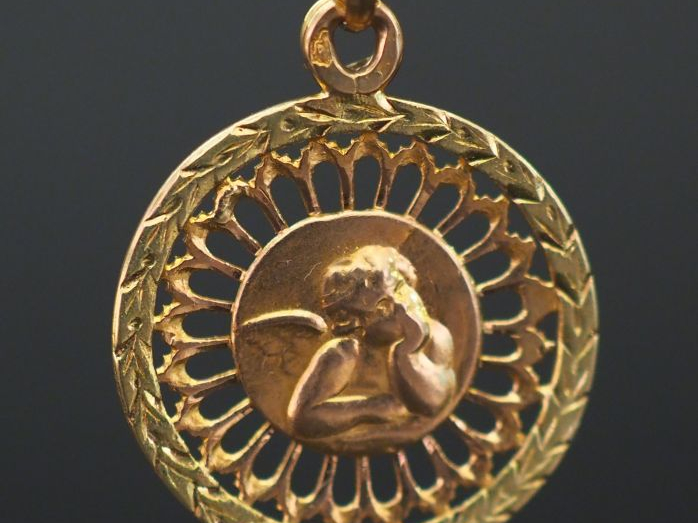 Petite médaille religieuse en or jaune ajouré, à  décor d’un angelot. 