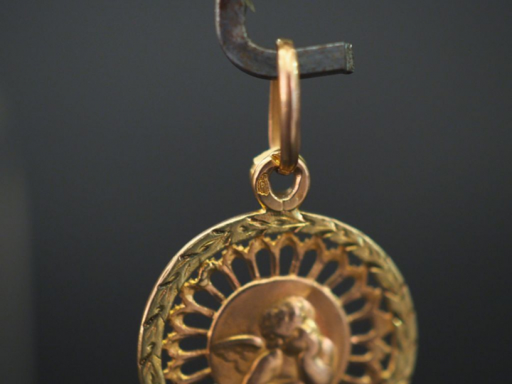 Petite médaille religieuse en or jaune ajouré, à  décor d’un angelot. 