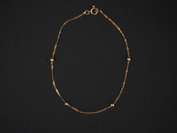 Petit bracelet en or jaune, à décor de quatre boules. Long. 17,5 cm Po