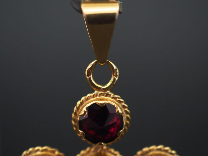 Pendentif en or jaune en forme de croix, sertie de six grenats. 3,4 x 