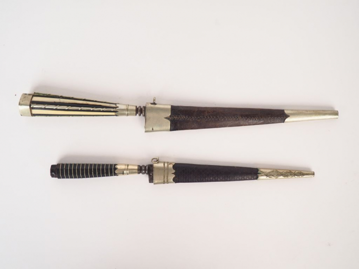 2 différents stylets à la génoise, avec leurs fourreaux. L. 26,1 cm. L