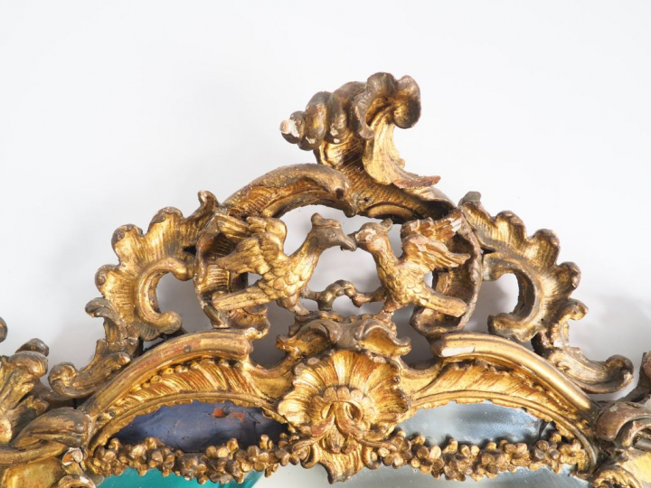 Glace Louis XV de style rocaille en bois sculpté et doré à décor de pa