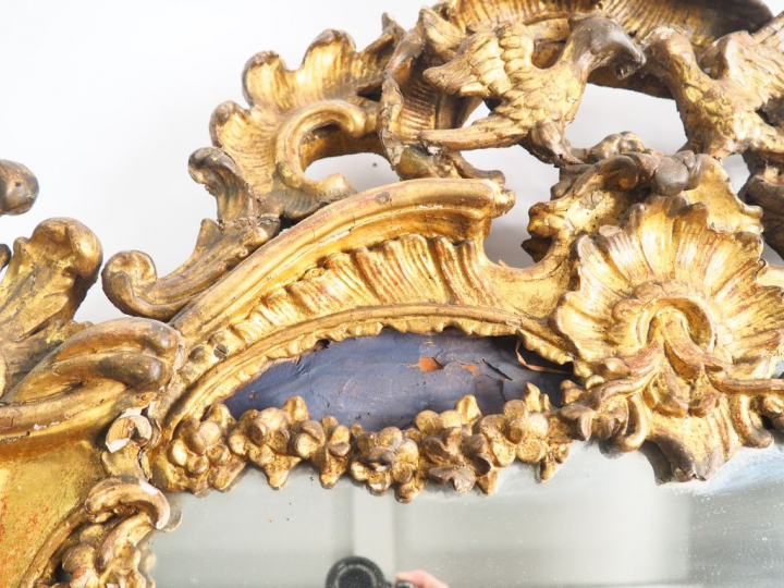 Glace Louis XV de style rocaille en bois sculpté et doré à décor de pa