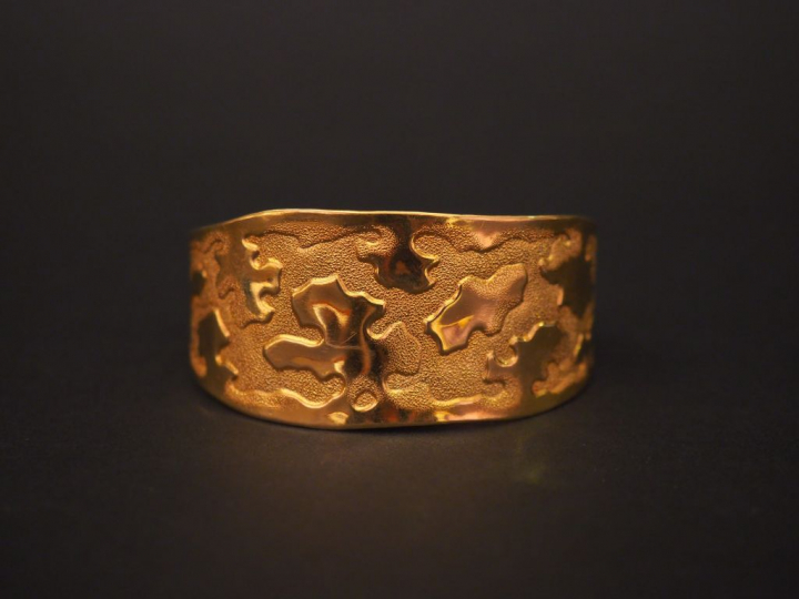 Bracelet jonc manchette en or jaune, à décor de motifs stylisés.  Poid