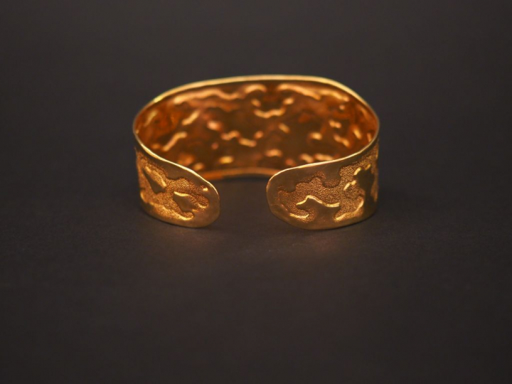 Bracelet jonc manchette en or jaune, à décor de motifs stylisés.  Poid