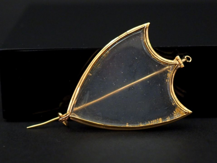 Une broche porte-photo en or jaune et verre en forme d’écu. 3,5 x 2,2 
