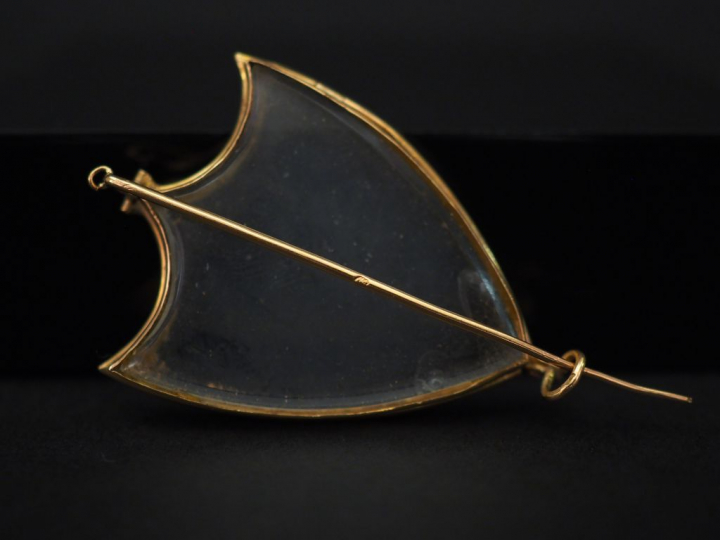 Une broche porte-photo en or jaune et verre en forme d’écu. 3,5 x 2,2 