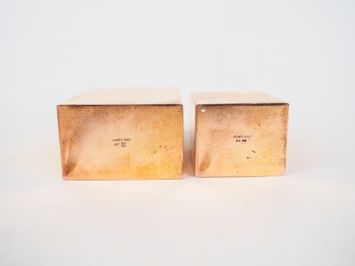 HERMES.  Deux différents flacons en métal doré. Signés. H. 11 cm et 8 