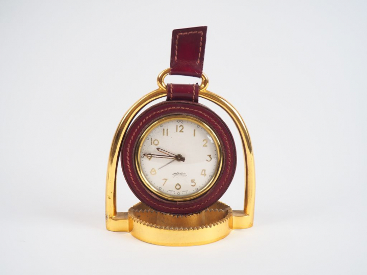 LONGCHAMP.  Pendulette en bronze et cuir en forme d'éperon.  Dim. 18 x