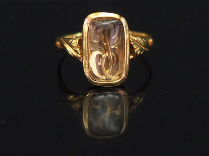 Bague en or jaune et verre, à décor de monogramme. La monture feuillag