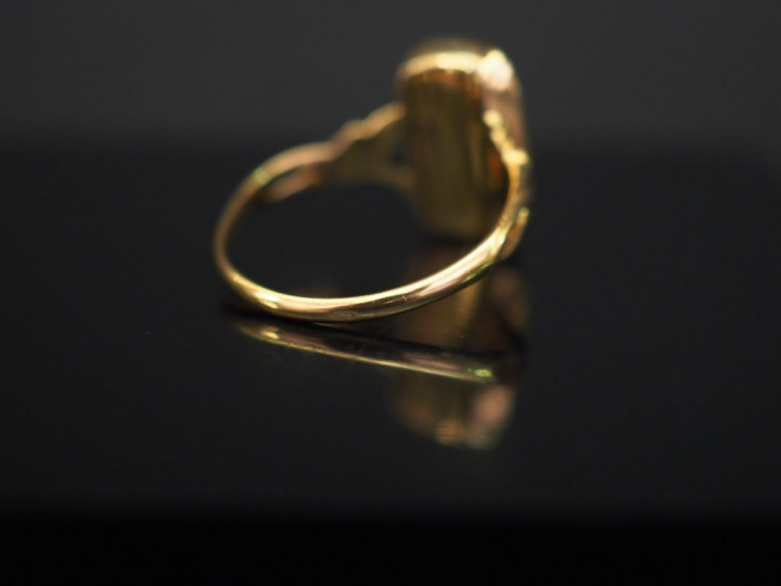 Bague en or jaune et verre, à décor de monogramme. La monture feuillag
