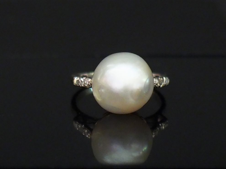 Bague en or blanc, sertie en son centre d'une perle blanche épaulée de