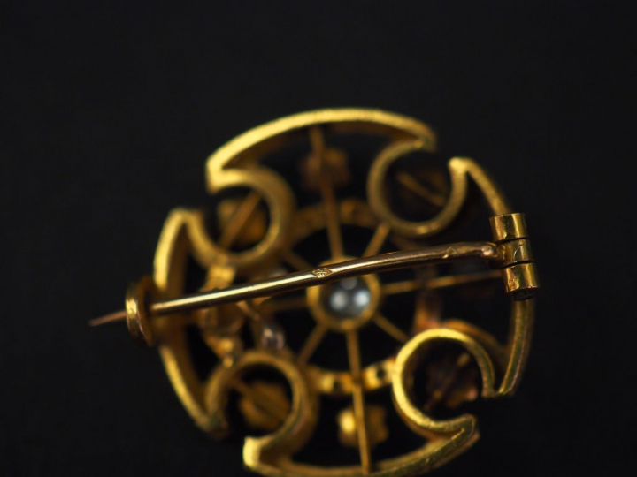 Broche ronde en or jaune, en forme de croix stylisée, sertie en son ce