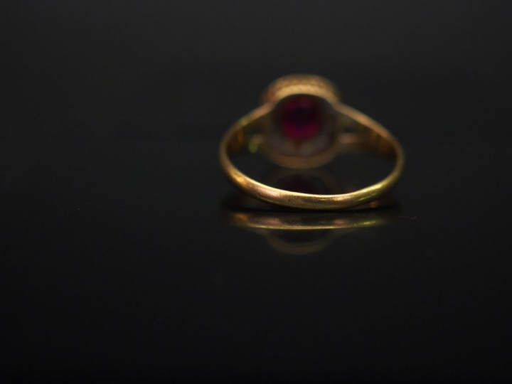Bague en or jaune, sertie en son centre d'une pierre rose entourée d'u