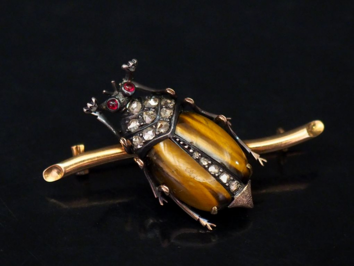 Broche en forme de scarabée posé sur une branche en or.  Le thorax ser