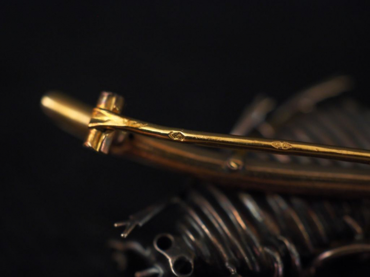 Broche en forme de scarabée posé sur une branche en or.  Le thorax ser
