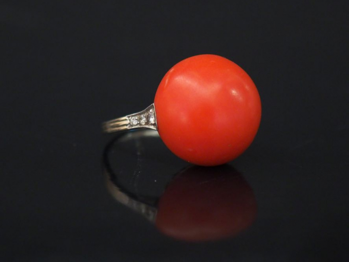 Bague en or blanc, sertie d'une boule de corail épaulée d'une ligne de