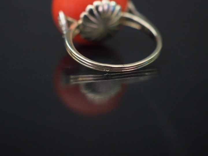 Bague en or blanc, sertie d'une boule de corail épaulée d'une ligne de