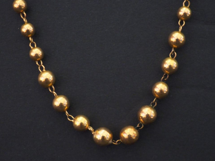 Collier souple en or jaune, à décor de boules disposées en chute. Long