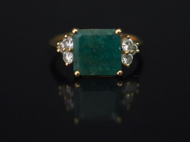 Bague en or jaune, sertie en son centre d'une émeraude épaulée de six 