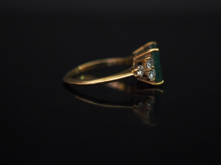 Bague en or jaune, sertie en son centre d'une émeraude épaulée de six 