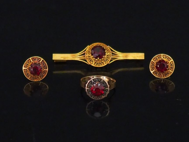 Parure en or jaune et pierres rouges, à décor filigrané. Comprenant : 