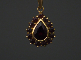 Vente aux enchères 	Pendentif en forme de goutte en or jaune, serti en son centre d’un gr
