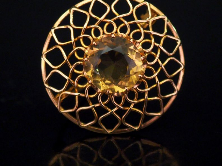 Broche circulaire en or jaune, à décor ajouré et sertie en son centre 