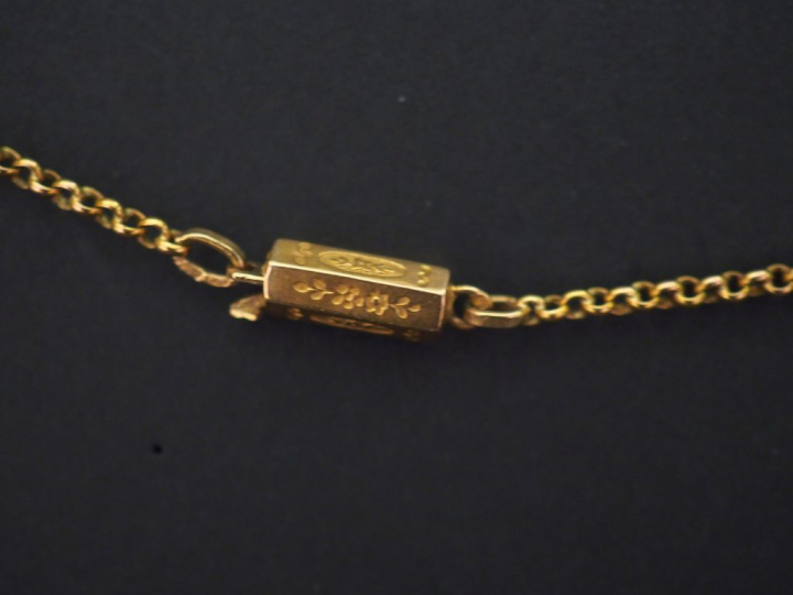 Chaine en or jaune, maille forçat. Joli fermoir, à décor de fleurs.  L