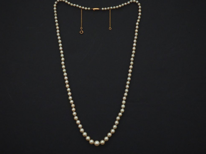 Collier de perles blanches disposées en chute. Fermoir et chainette de