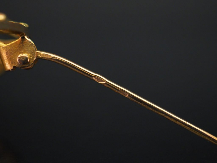 Broche circulaire en or jaune, à décor ajouré et sertie en son centre 